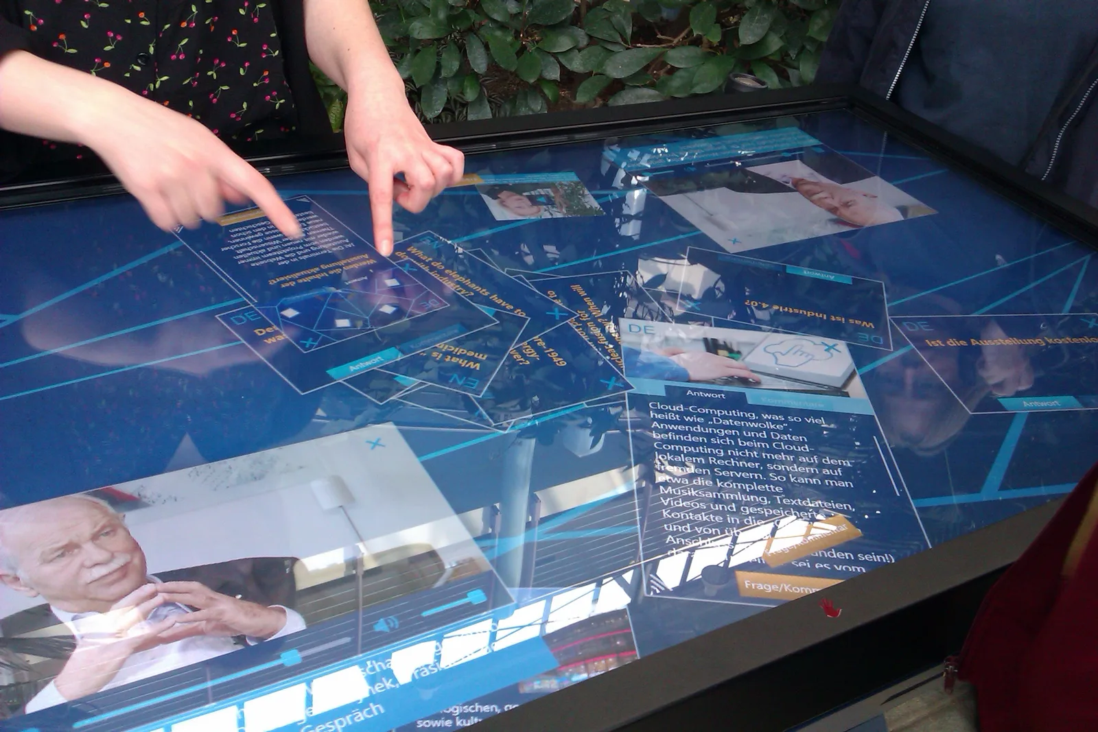Two people point at cards on a large touchscreen table
