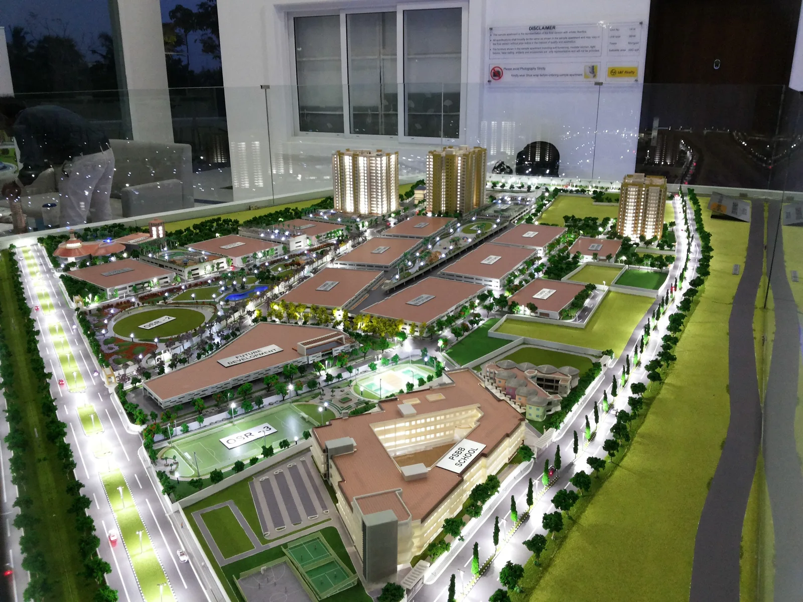 Illuminated physical scale model of a large development, with building volumes, roads and landscaping
