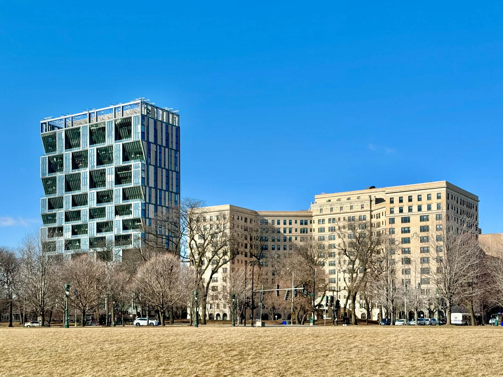 Modern and beige buildings beside a grassy park under blue sky